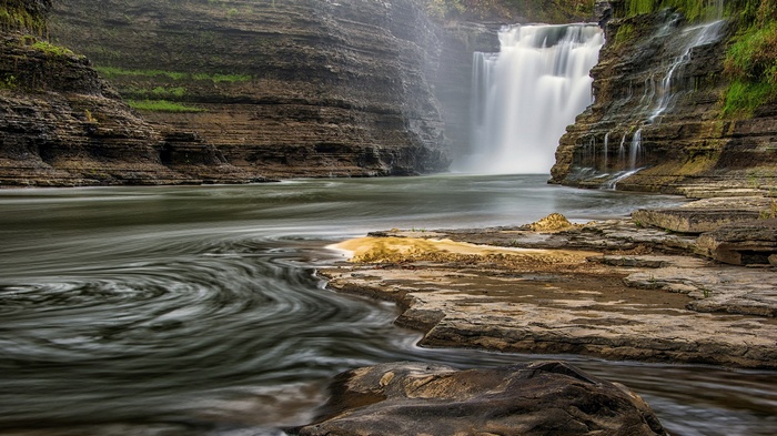 Waterfall cascading into a river canyon
