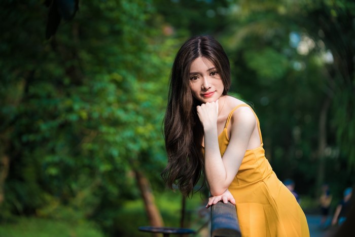 Asian woman in yellow dress posing outdoors