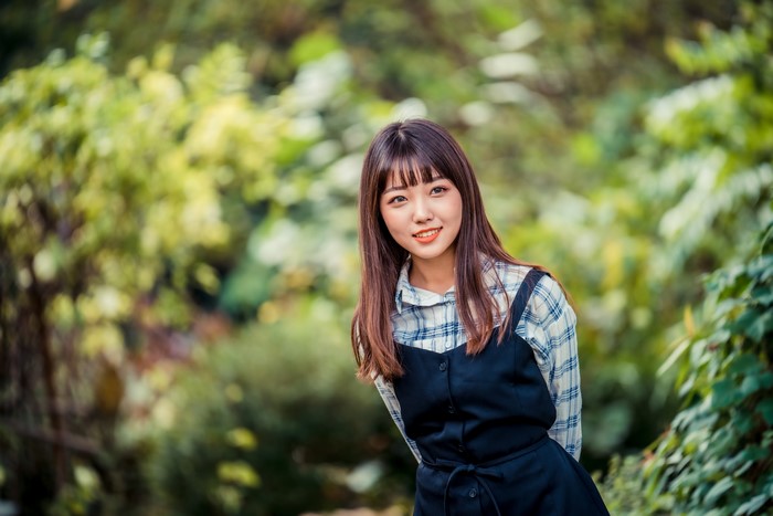 Asian girl with brown hair smiling in a park