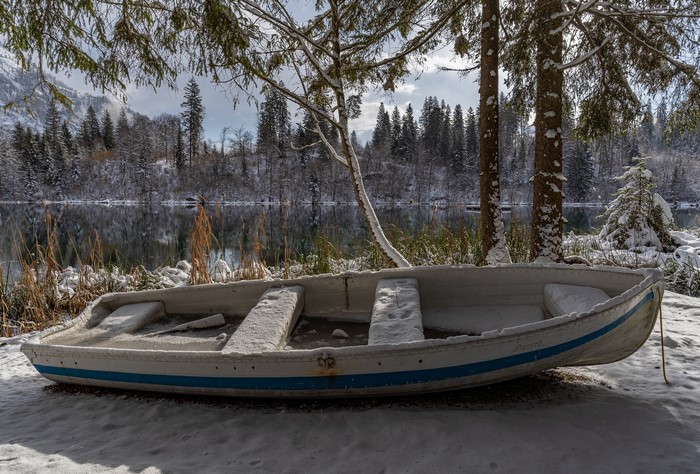 Boat on a snowy shore by a lake in winter