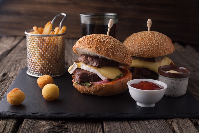 Two gourmet burgers with fries and dipping sauces