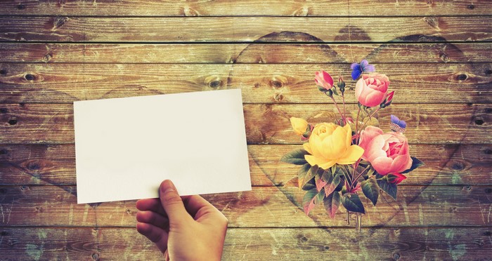 Hand holding paper with roses on wood planks