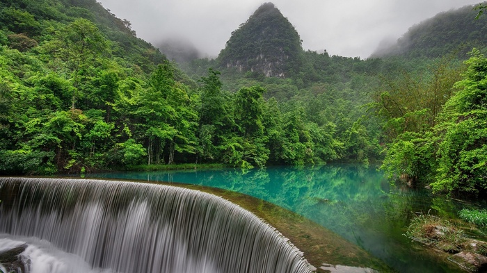 Waterfall and turquoise water in a lush green forest
