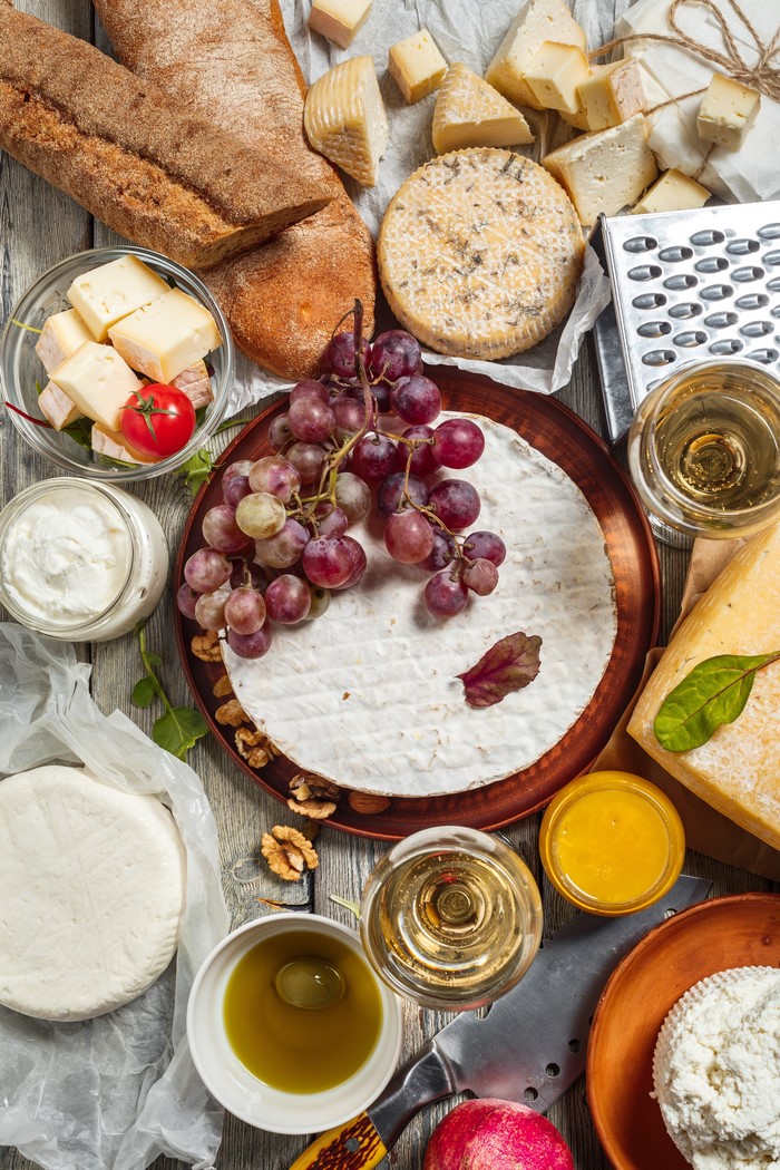 Cheese board with bread, grapes, wine, and olive oil