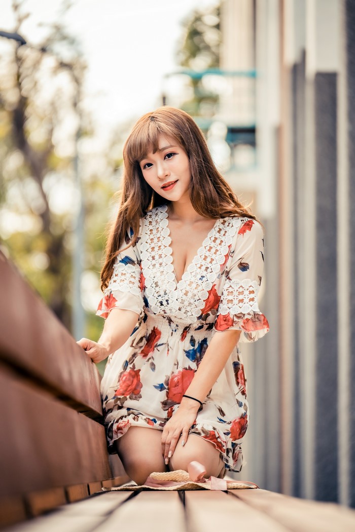 Asian woman in floral dress sitting on a bench
