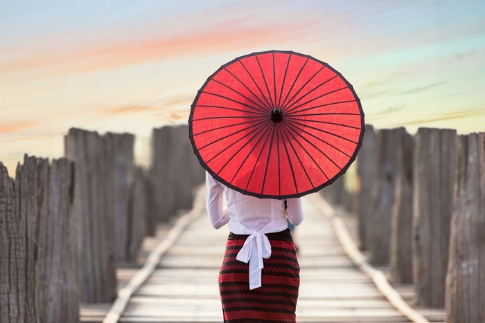 Woman with red umbrella on wooden bridge