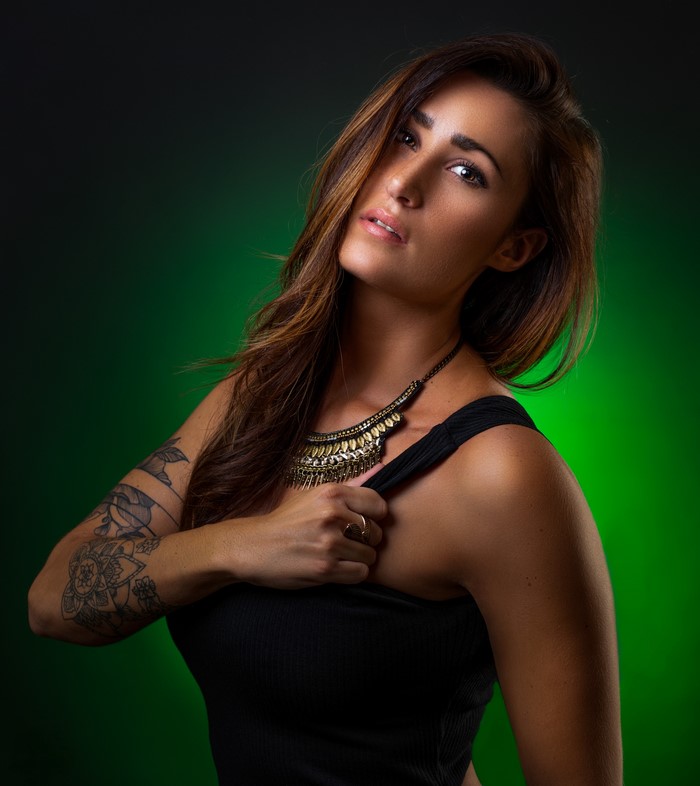 Woman with tattoos and necklace on green background
