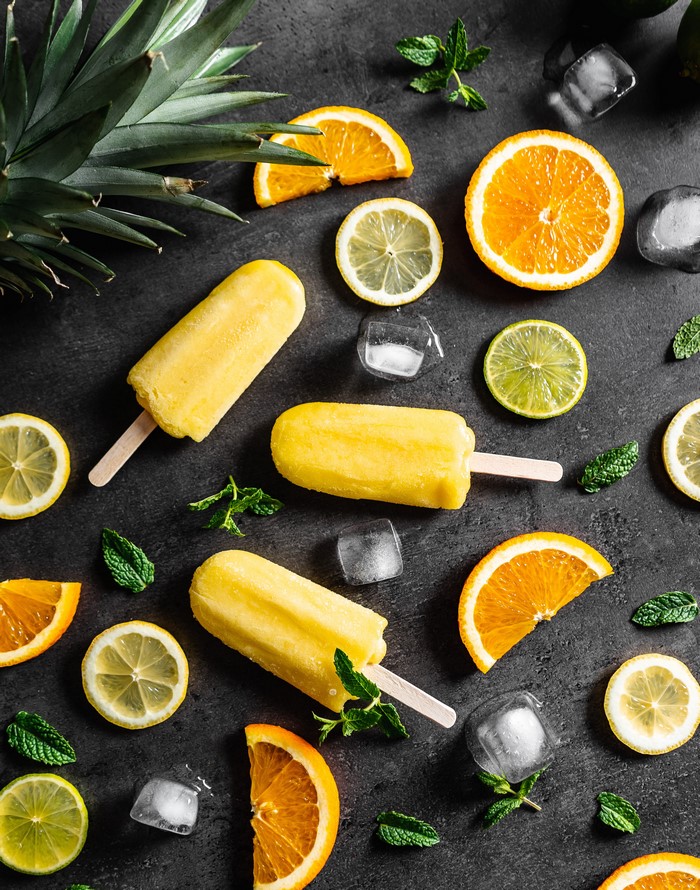 Yellow popsicles with oranges, lemons, limes, mint, and ice