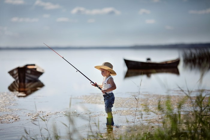 Boy fishing with a rod near boats