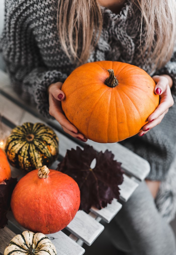 Woman holding a pumpkin with other pumpkins