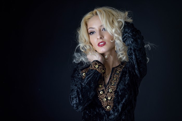Blonde woman in black dress with gold embroidery