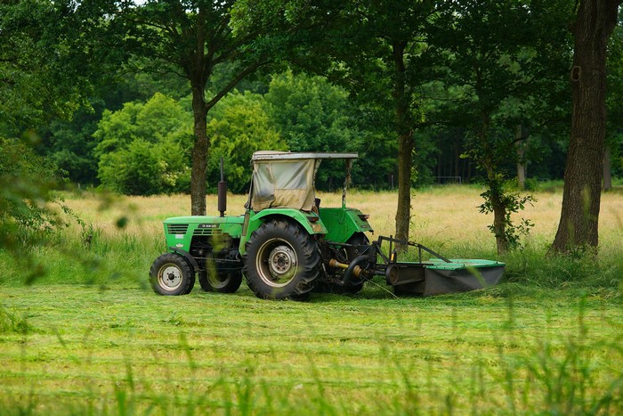 Green tractor mowing a field
