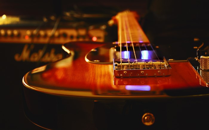 Closeup of a sunburst electric guitar and Marshall amplifier