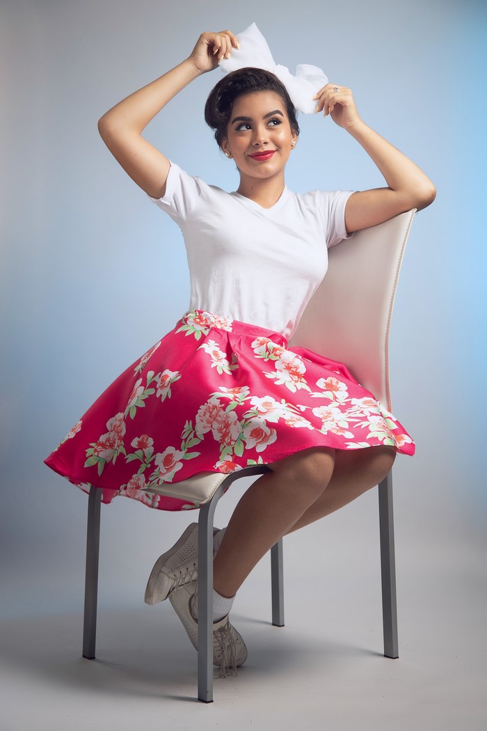 Brunette girl with bowknot sitting on chair