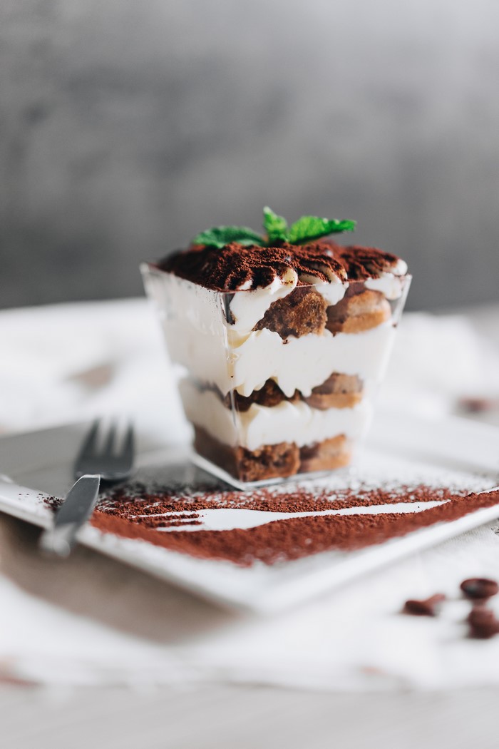 Tiramisu dessert in a glass with cocoa powder and mint