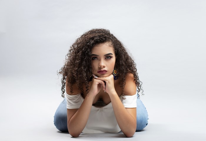 Camila with curly hair posing on a gray background