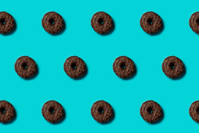 Chocolate donuts with sprinkles on a teal background
