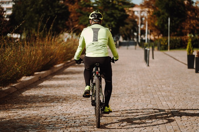 Man riding a bicycle on a cobblestone path
