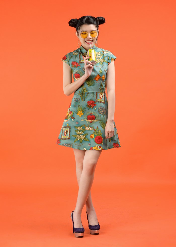 Woman in a patterned dress drinking from a can