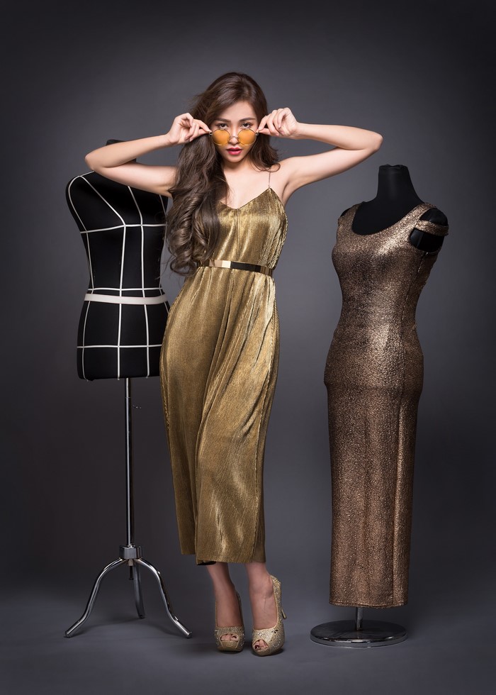 Asian model in gold dress with sunglasses and mannequins