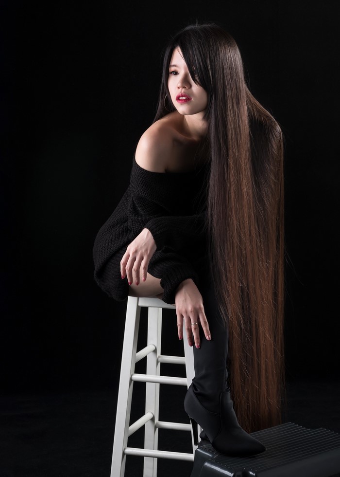 Asian woman with long hair sitting on a stool