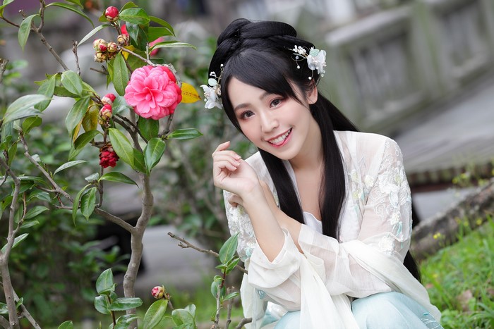 Brunette girl in traditional Asian attire with camellia flowers