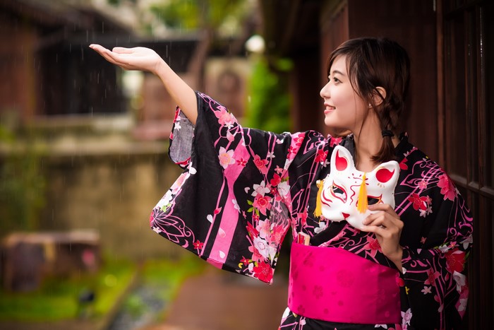 Woman in Kimono Holding a Mask in the Rain
