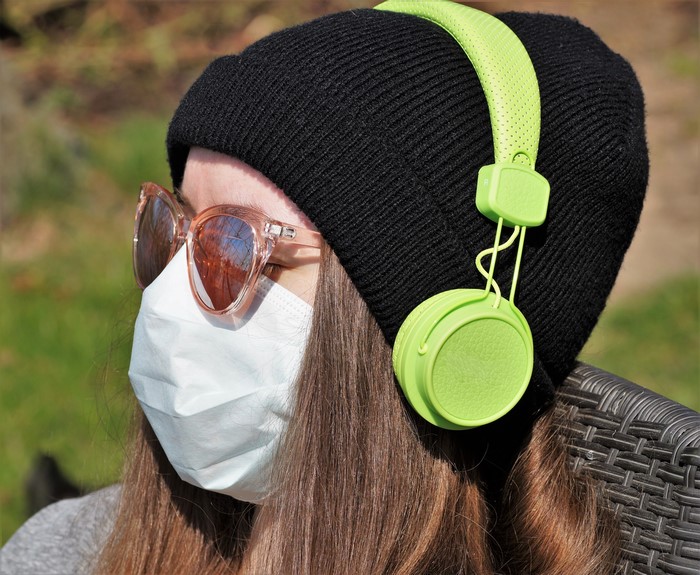Person wearing mask, headphones, and beanie