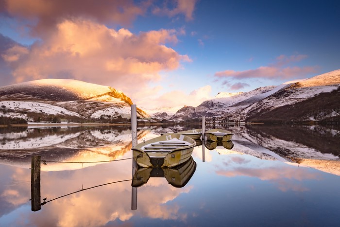 Boats on a lake with snow-capped mountains and clouds