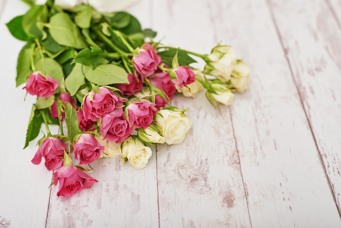 Bouquets of pink and white roses on wood planks