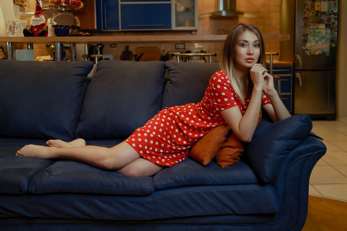 Woman in red polka dot dress lying on a sofa