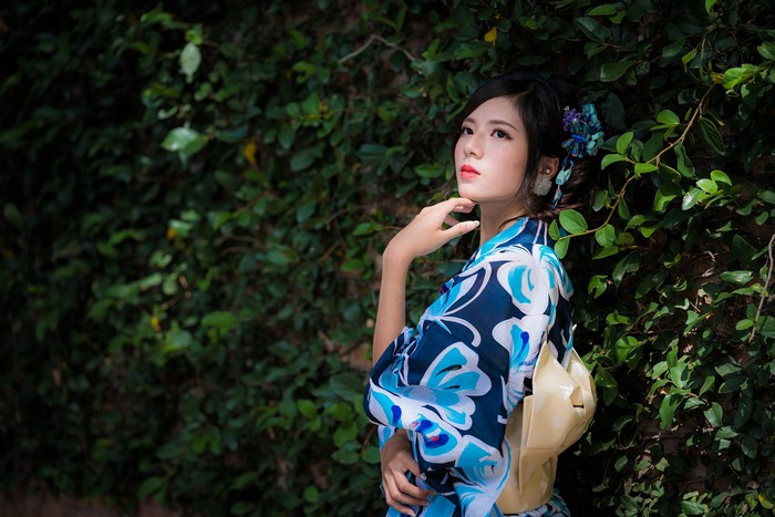 Woman in Kimono Poses by Green Foliage