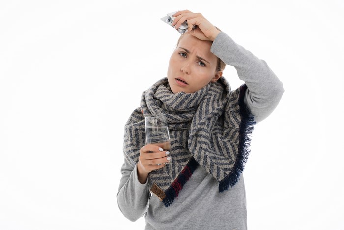 Woman with scarf holding pills and glass of water