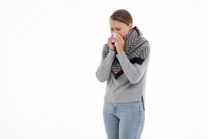 Woman with runny nose blowing into tissue