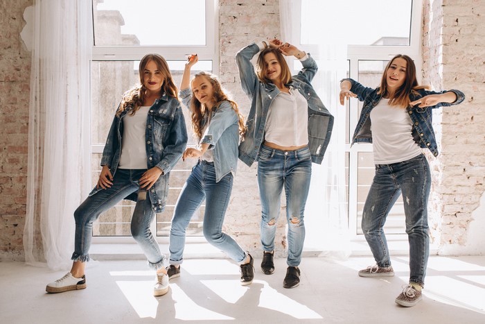 Four young women in denim outfits dancing