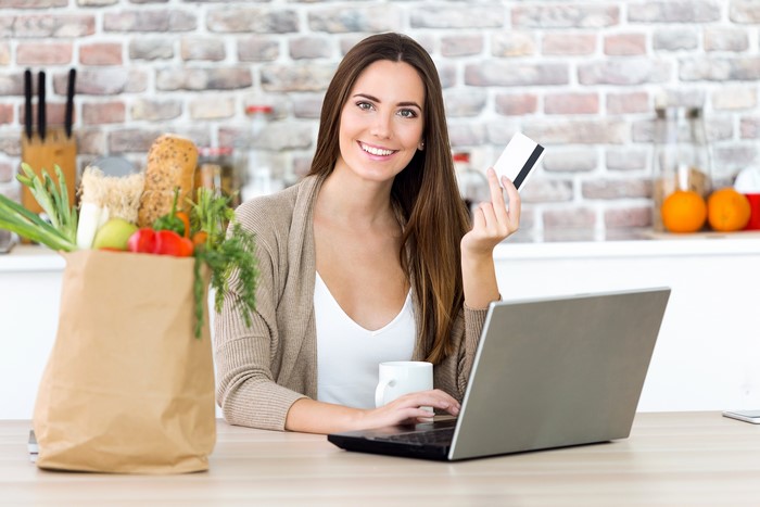 Woman with credit card and laptop with groceries