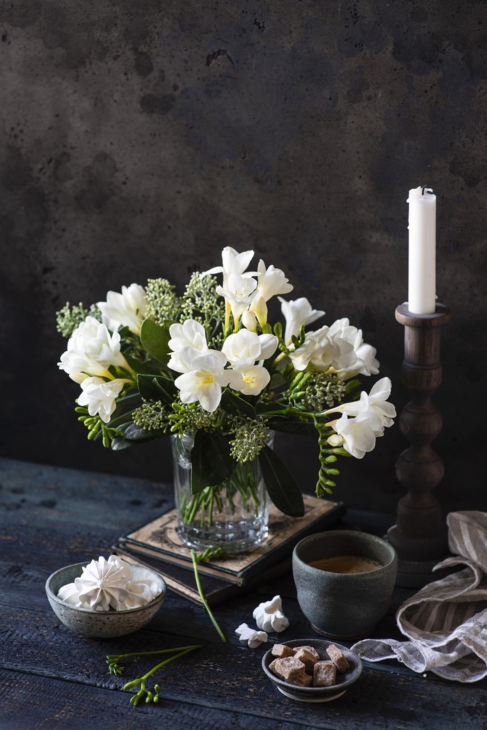 White Freesia flowers in a vase with coffee and sugar cubes