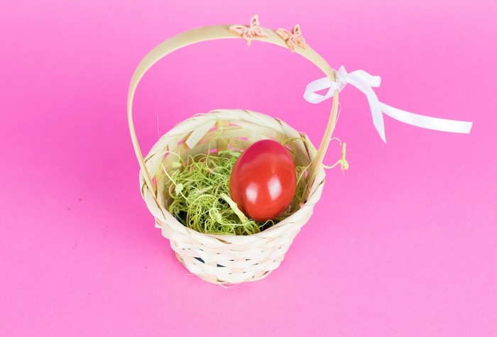 Easter egg in a wicker basket with butterflies and ribbon