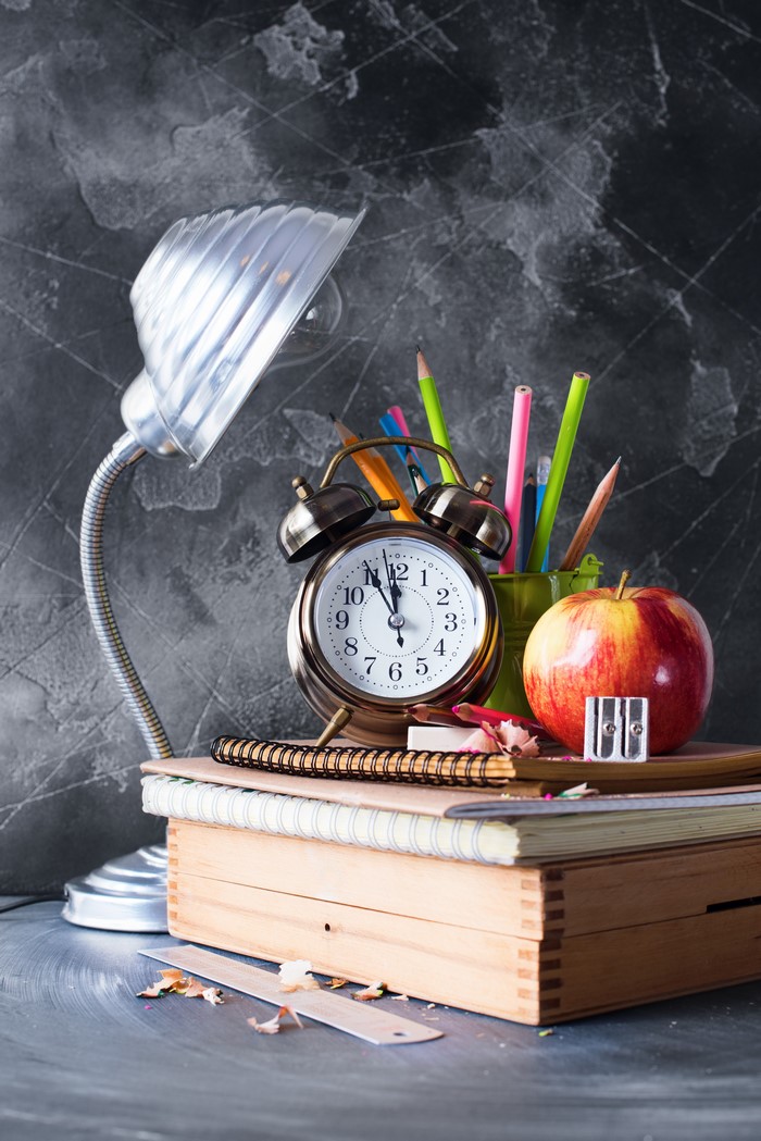 Desk lamp, alarm clock, apple, pencils, notebooks, and wooden box