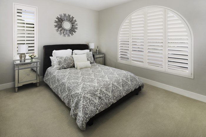 Bedroom with bed, pillows, and arched window
