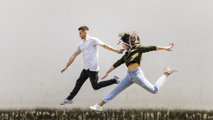 Man and woman jumping in front of a wall