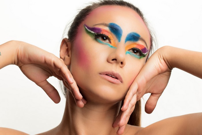Woman with colorful face paint and hands near face