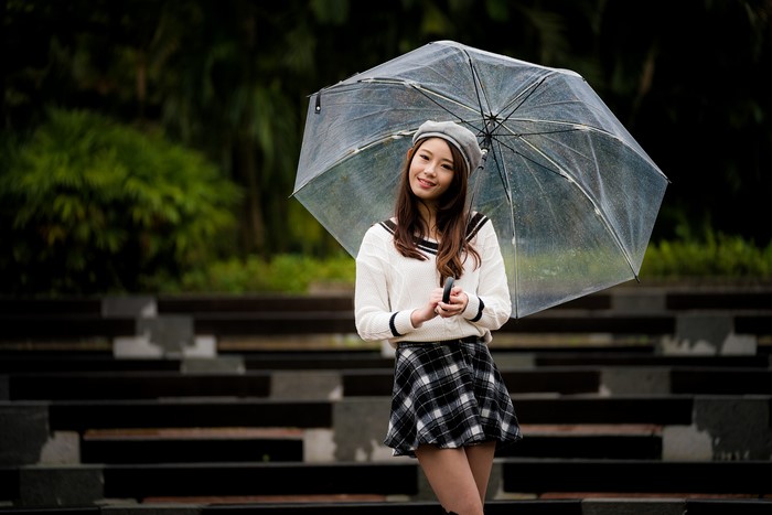 Asian woman with umbrella wearing skirt and sweater