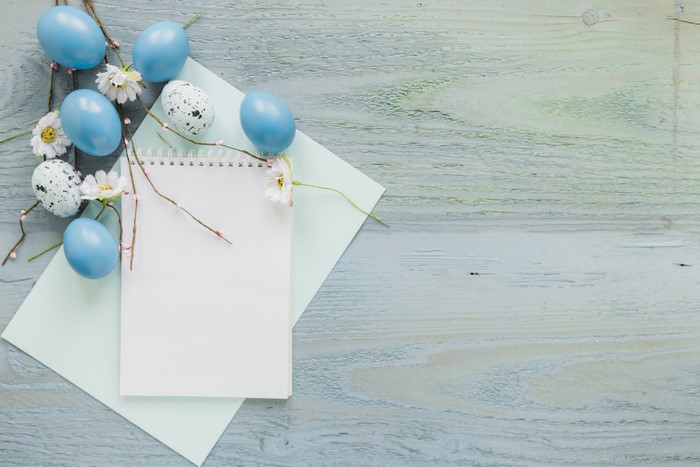 Easter eggs and notepad on wooden planks
