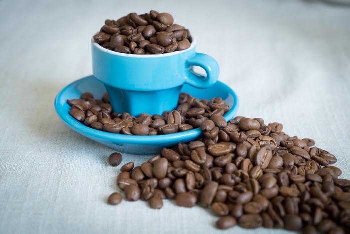 Blue coffee cup filled with coffee beans