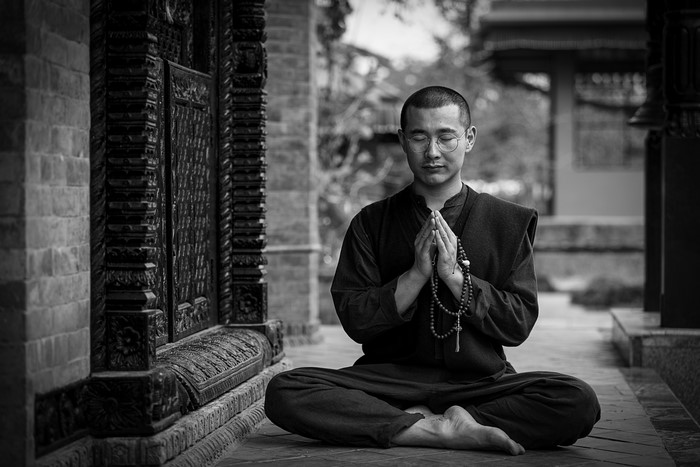Monk meditating in lotus position with prayer beads