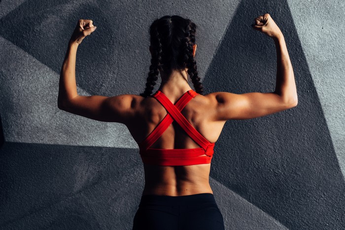 Woman flexing arms in red sports bra