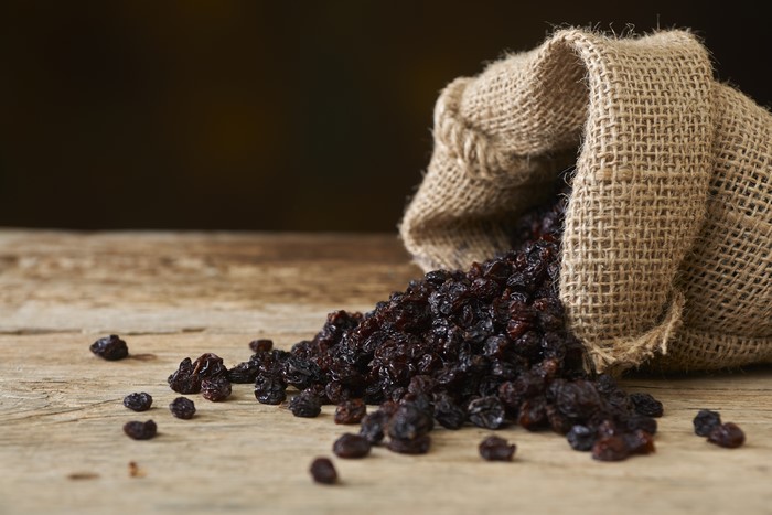 Raisins spilling from a burlap sack onto a wooden table