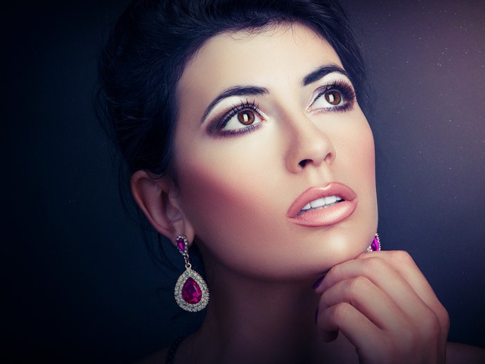 Woman with dramatic makeup and pink earrings