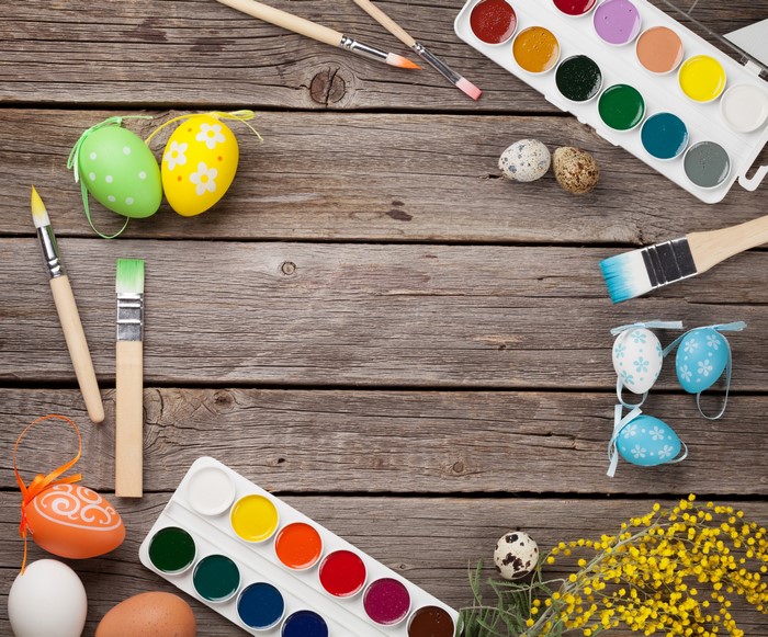 Easter eggs and painting supplies on wood